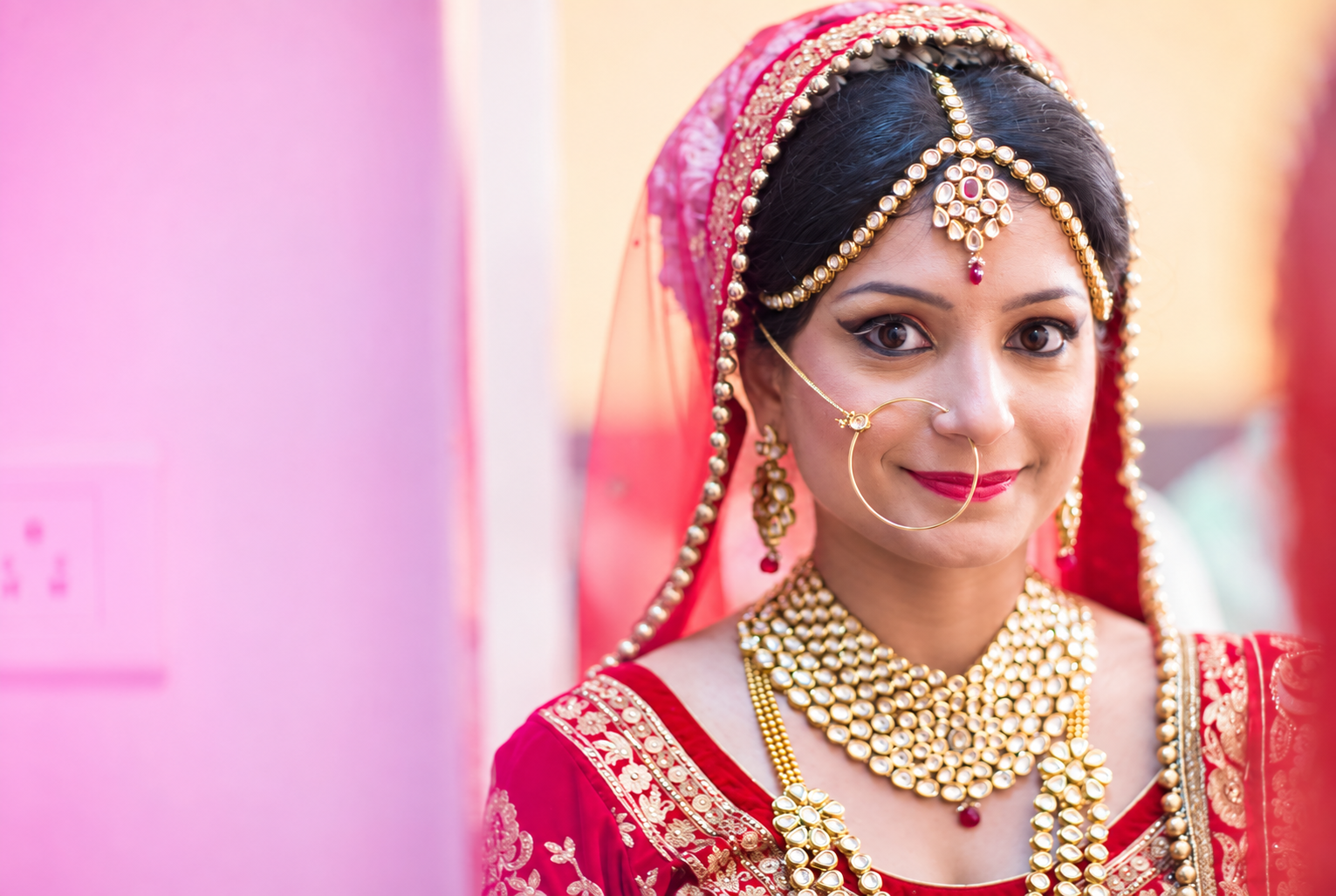 Regal Indian bride adorned in traditional red lehenga and heritage gold jewellery by Achintya Studio